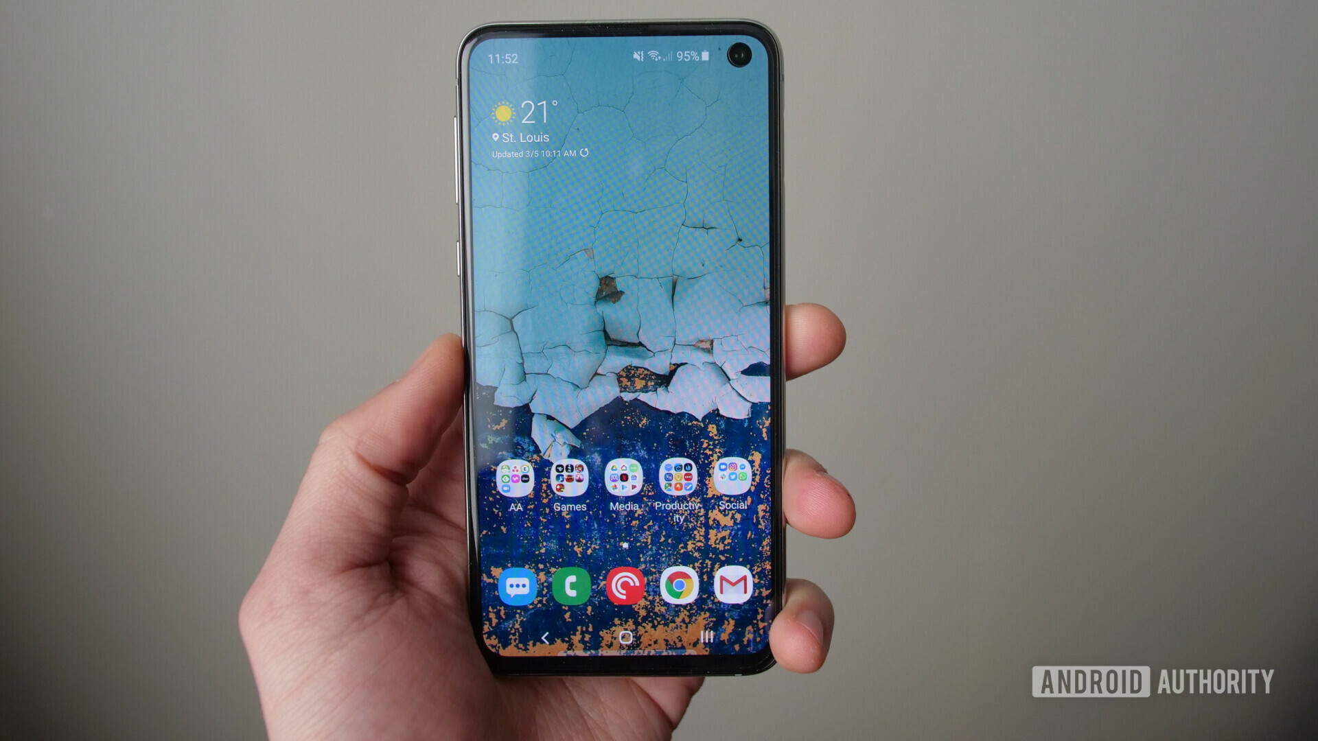 Front side of the samsung galaxy s10e held in hand, with display turned on showing the ONE UI software.