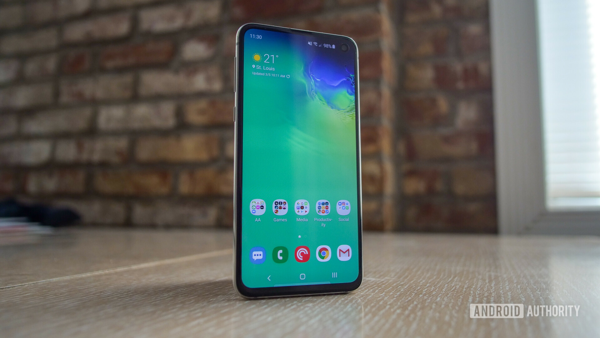 Front side photo of the samsung galaxy s10e standing upright with the display turned on running on android pie.