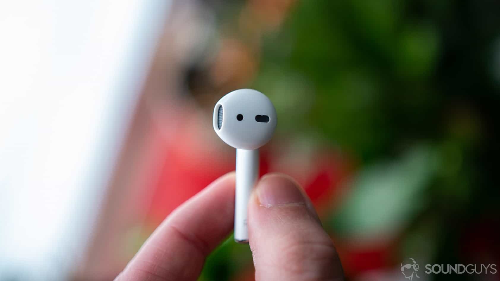 Apple's new AirPods with the right earbud between a man's fingers.