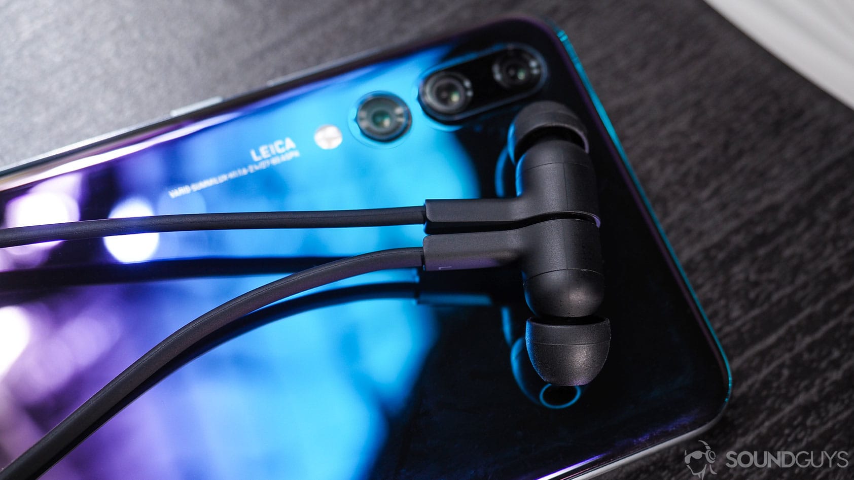 Huawei Freelace: close-up of earbuds magnetized together atop Huawei P20 smartphone.