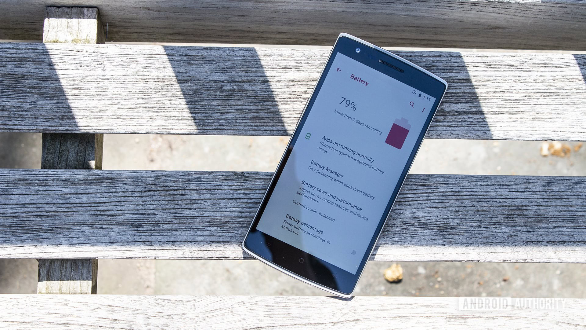 A OnePlus One on a bench with the battery settings page pulled up.