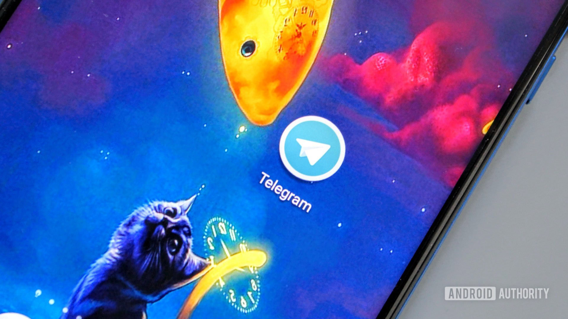 The Telegram icon on an Honor View 20 on a blue background with a cat and a fish.