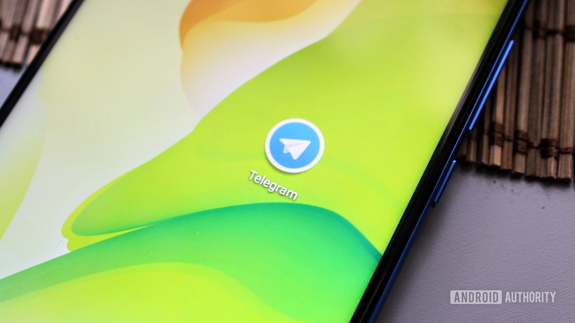 The Telegram icon on an Honor View 20 on a green background.
