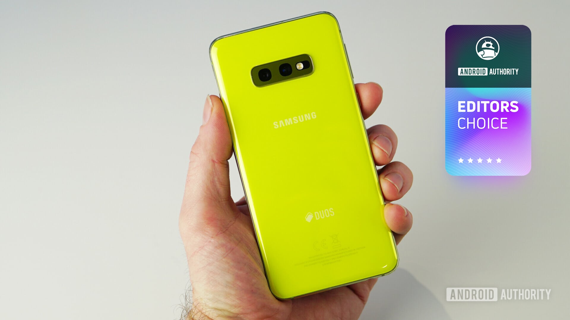 A yellow Samsung Galaxy S10e held in a man's left hand.