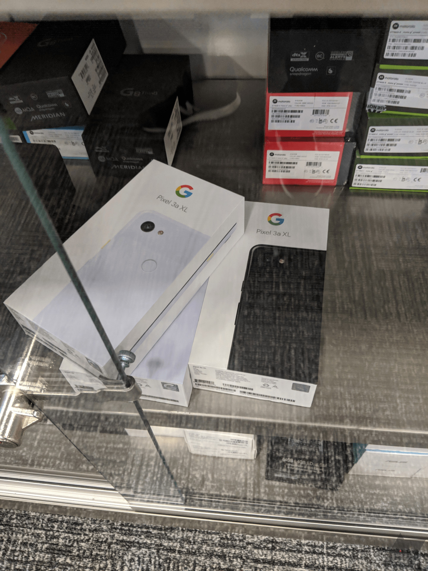 A stack of Google Pixel 3a XL boxes in a Best Buy store cabinet.