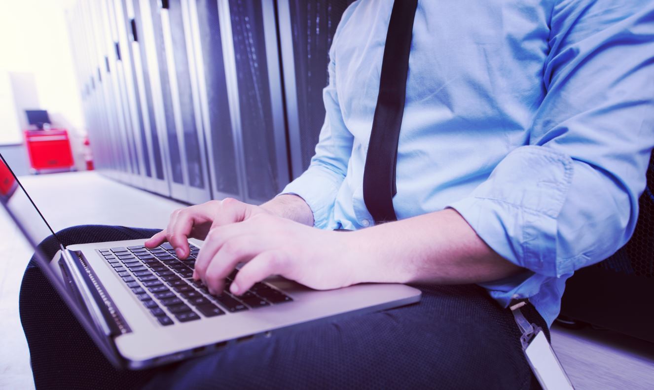 SQL Database engineer working on a laptop in server room