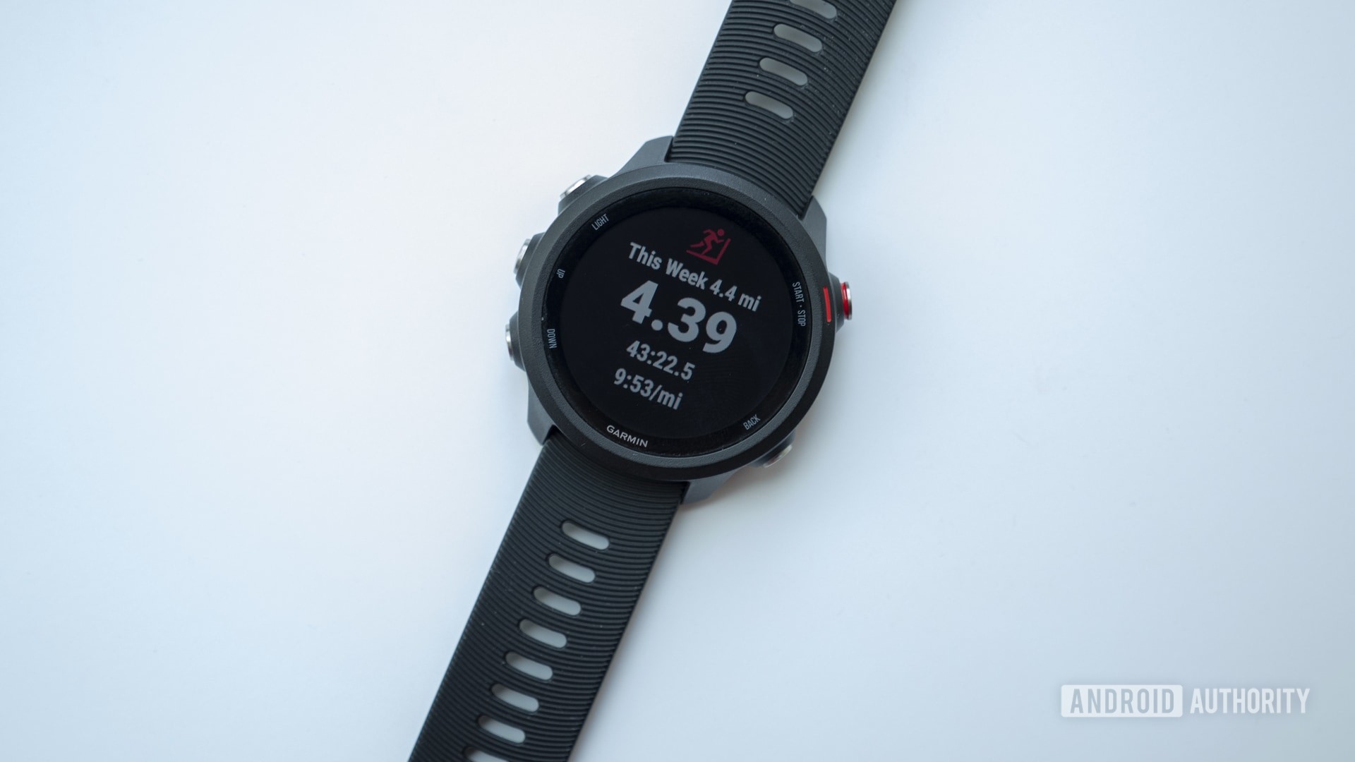 A Garmin Forerunner 245 Music running watch rests on a white surface displaying its activities screen.