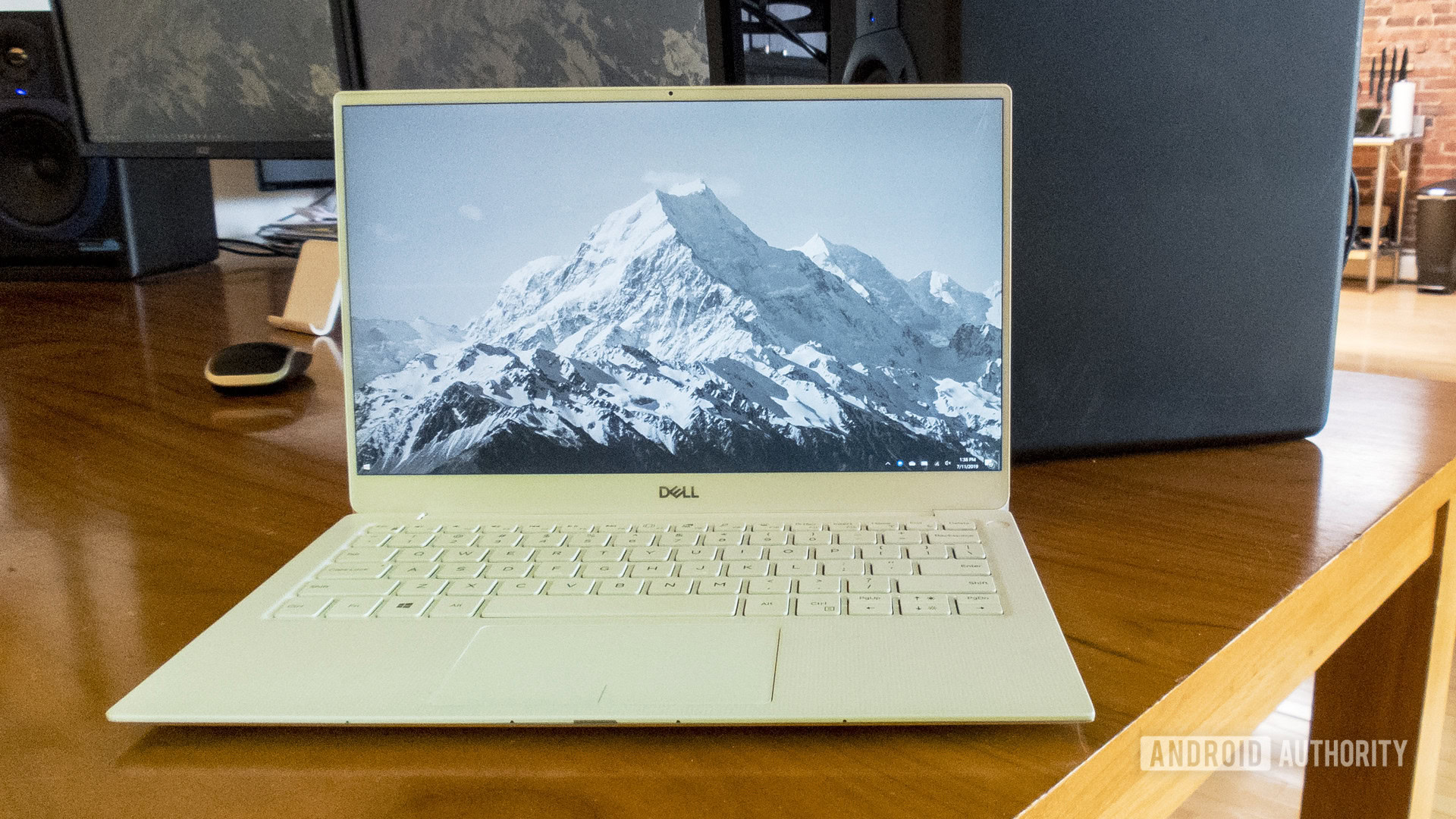 A Dell XPS 13 2019 edition sitting open on a desk with a mountain landscape photo as the background.