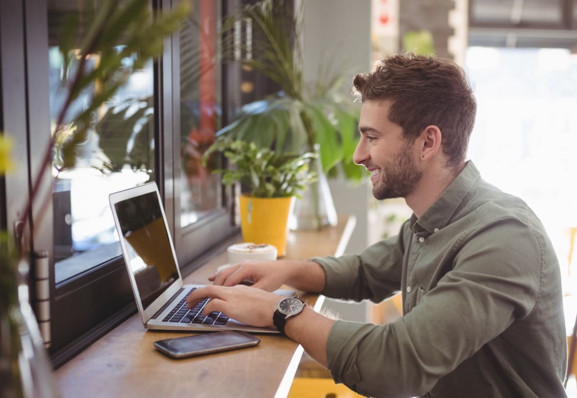 Man typing or coding on laptop in coffee shop feature