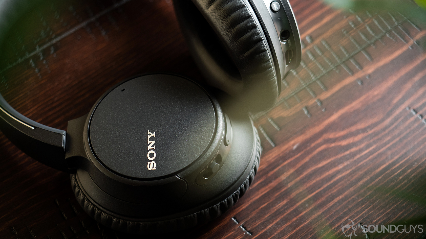 Sony WH-CH700N headphones on a cherry wood surface.