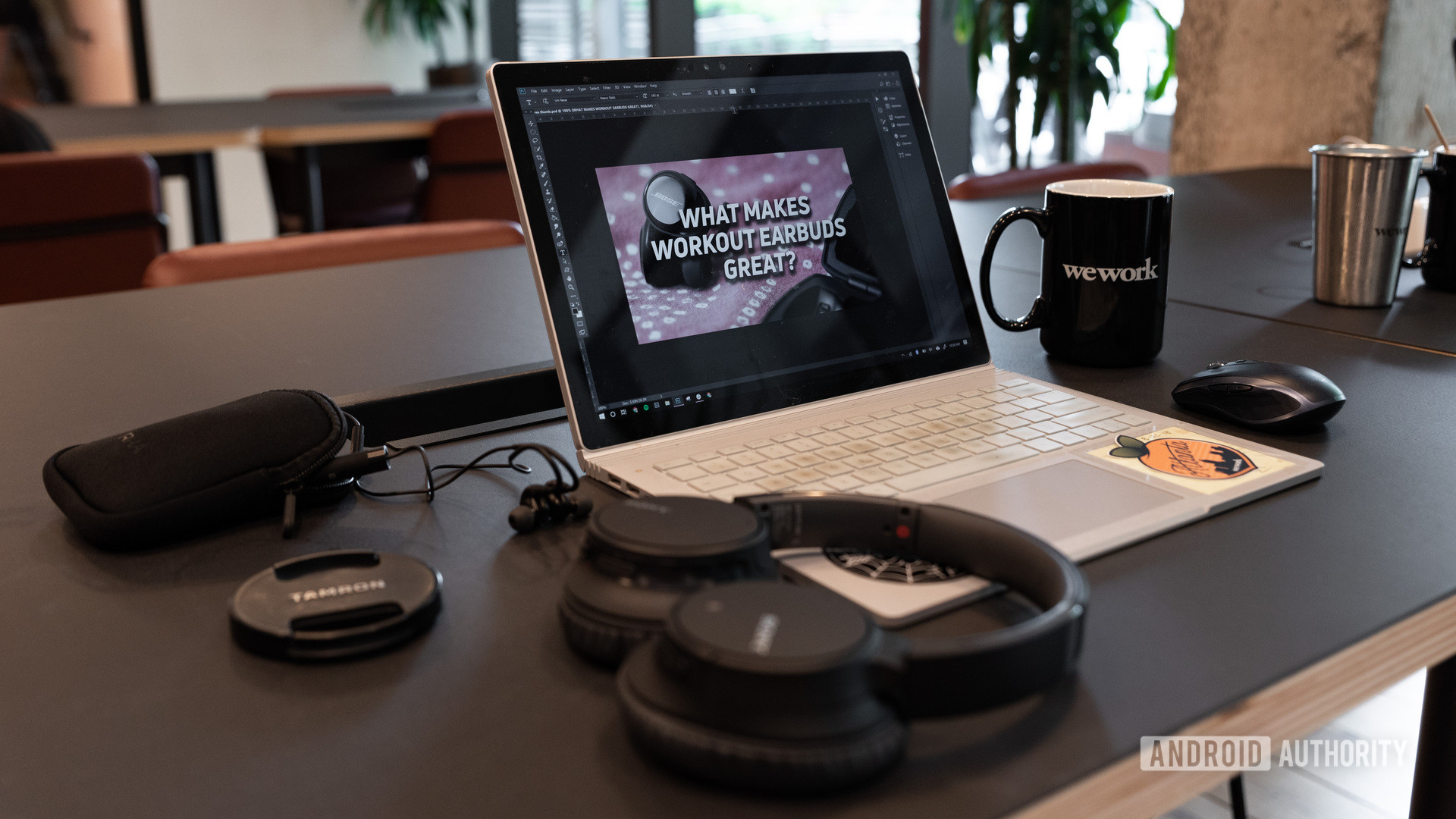 A laptop with Photoshop open and a set of Sony ANC headphones with a ceramic mug in the background.