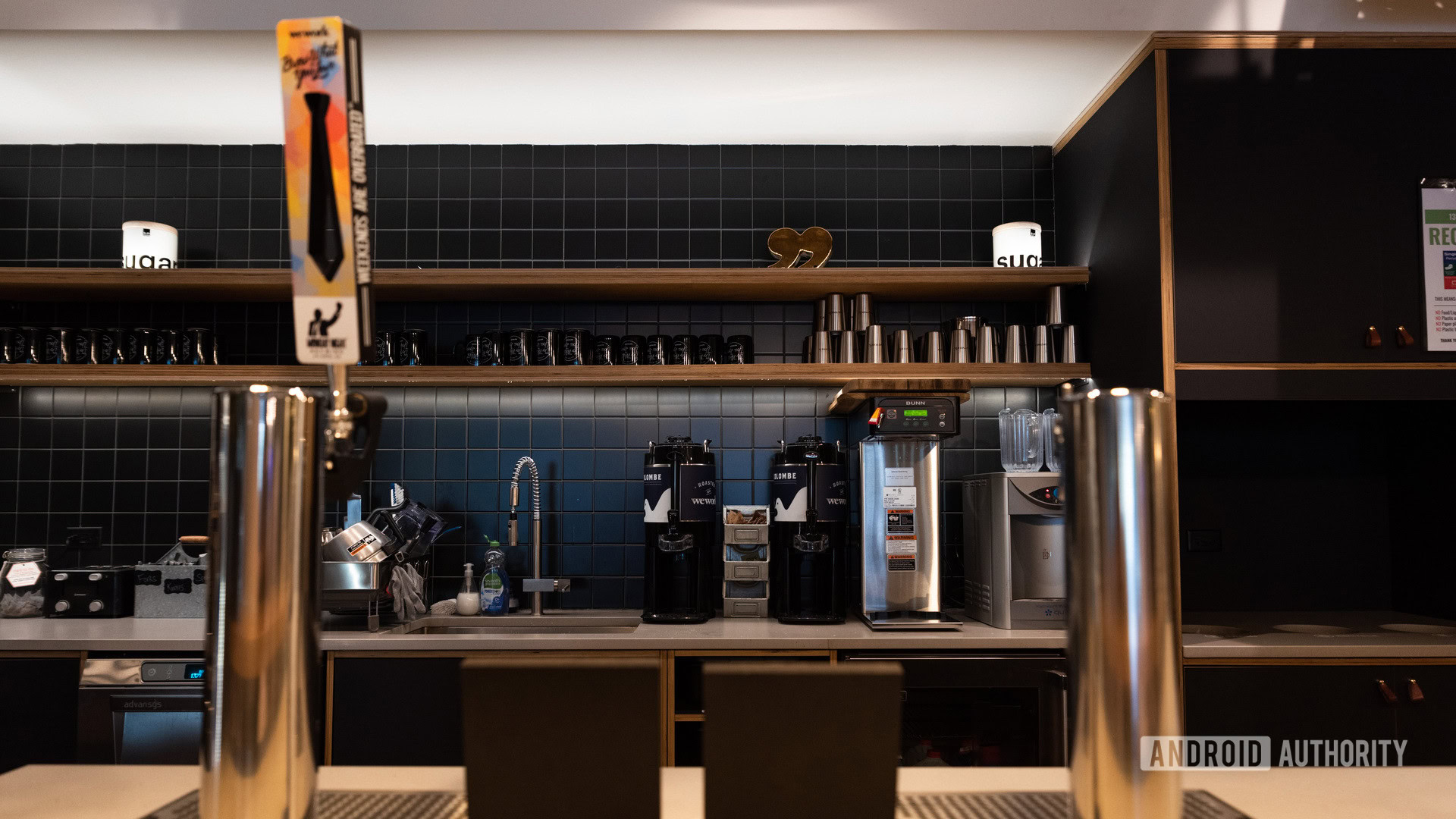 Beer taps in a WeWork with kitchen appliances in the background.