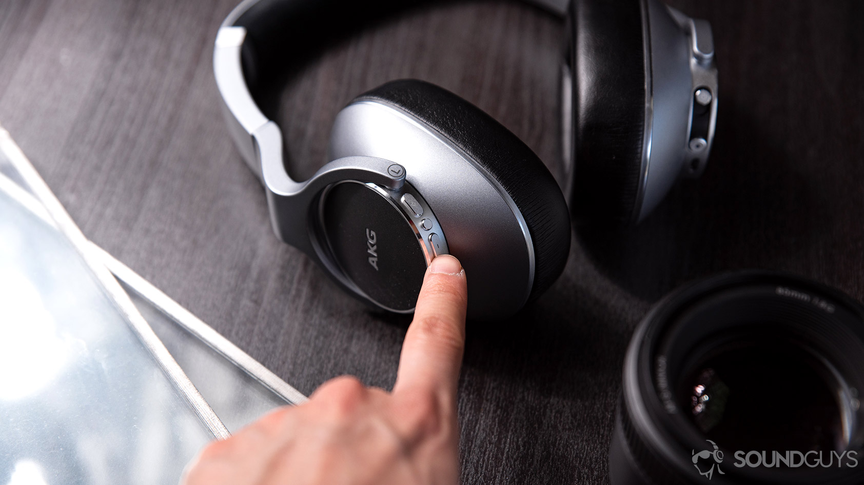 A hand reaching out for the volume controls on the left ear cup of the AKG N700NC.