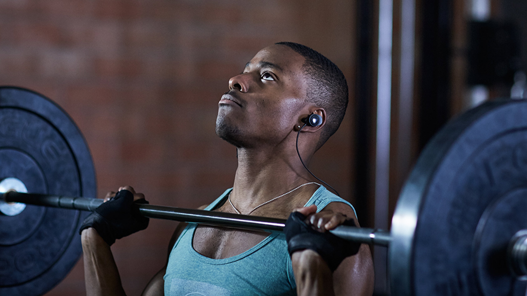 Bose SoundSport Pulse Wireless heart rate monitor earbuds lifestyle image of a man weight lifting.
