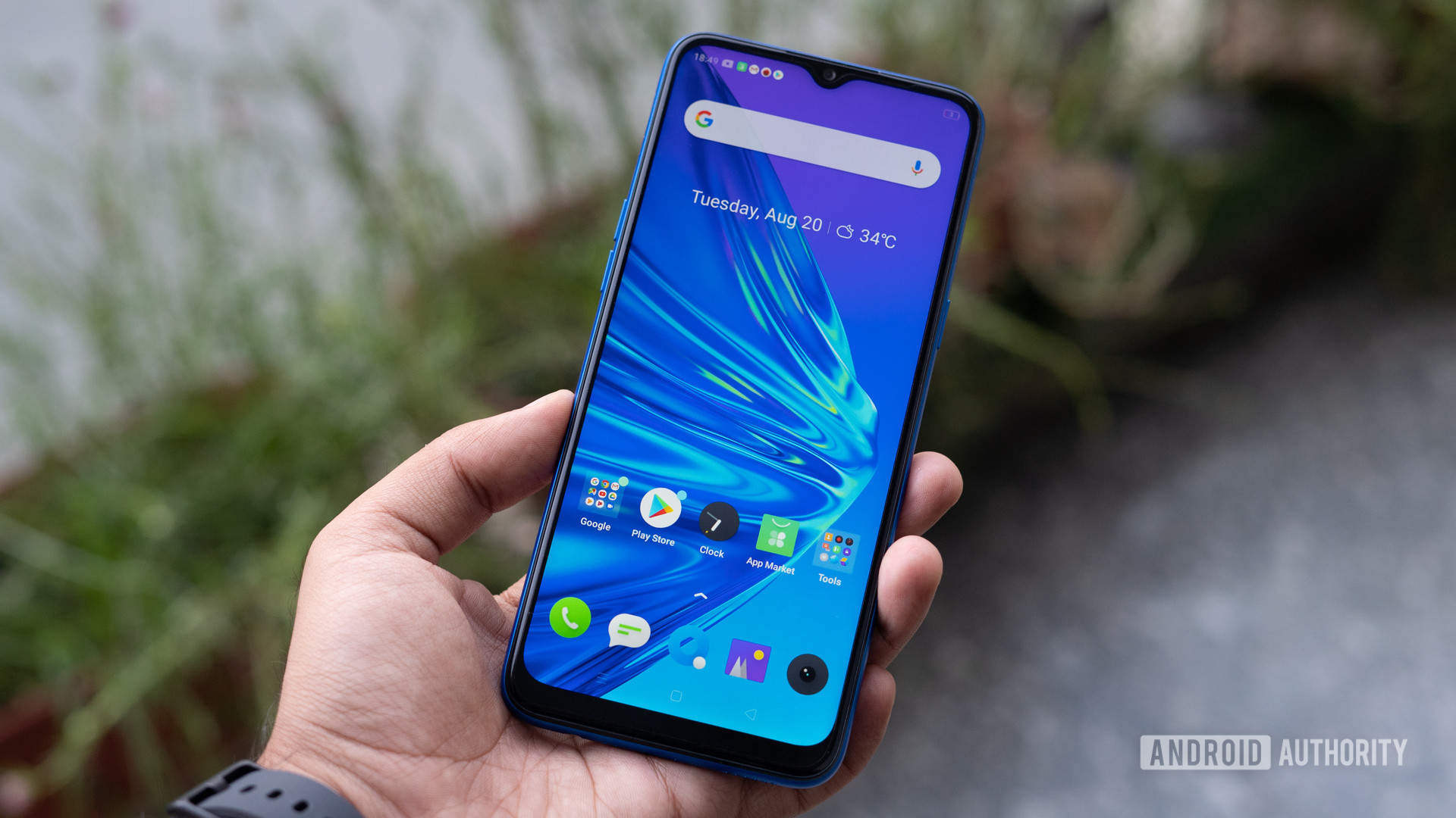 realme 5 in hand showing display and homescreen