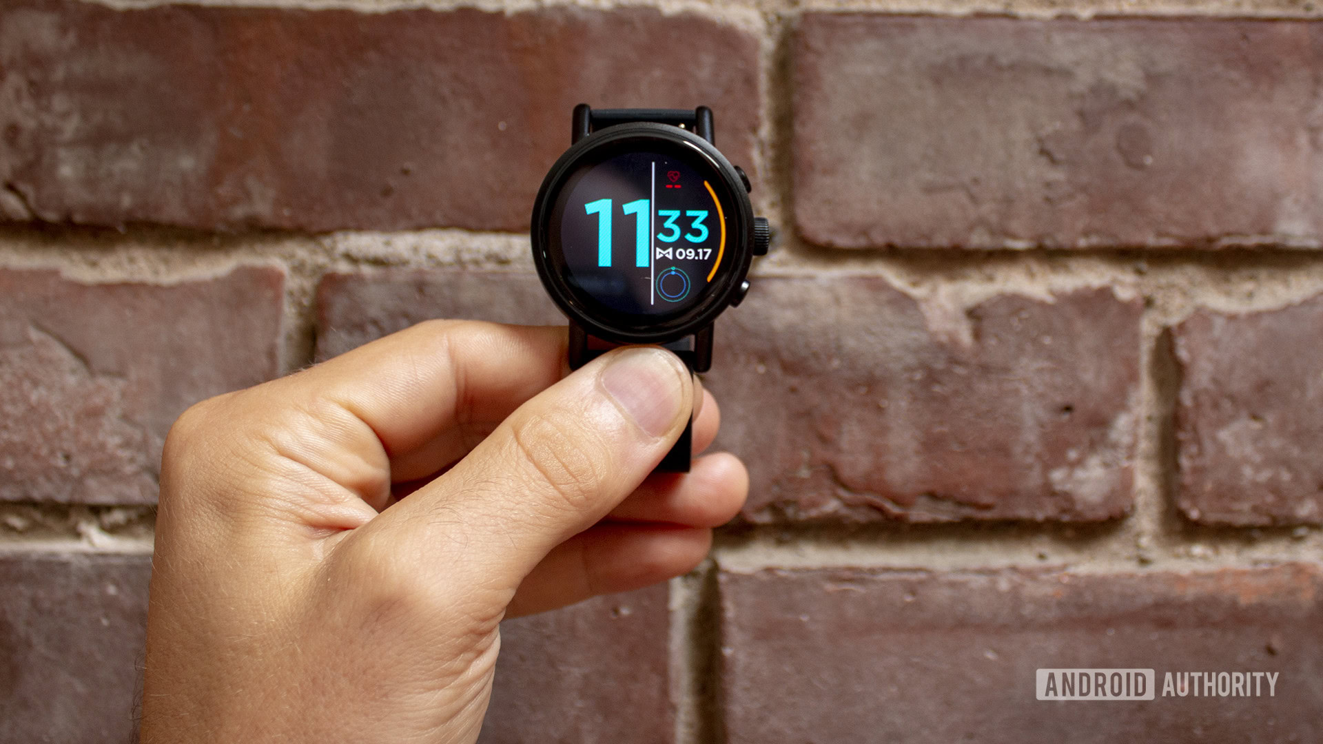 Misfit Vapor X Smartwatch Held in Hand Against Brick Wall