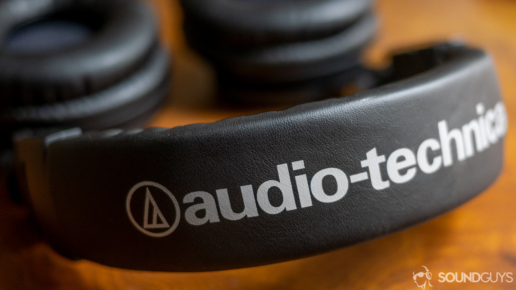 A photo of the Audio-Technica ATH-M50xBT on a wooden desk.