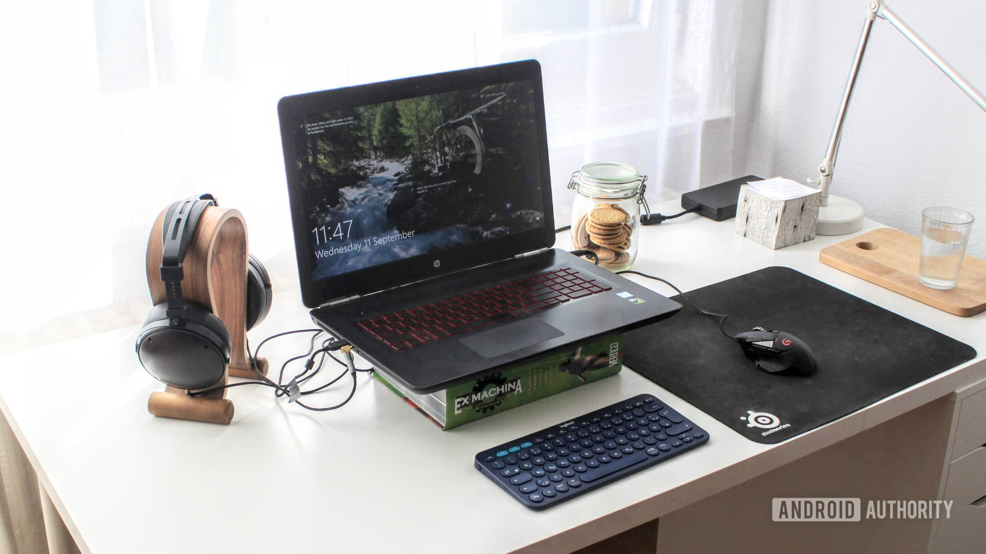 a latpop, desk, headset, mouse and book on a table