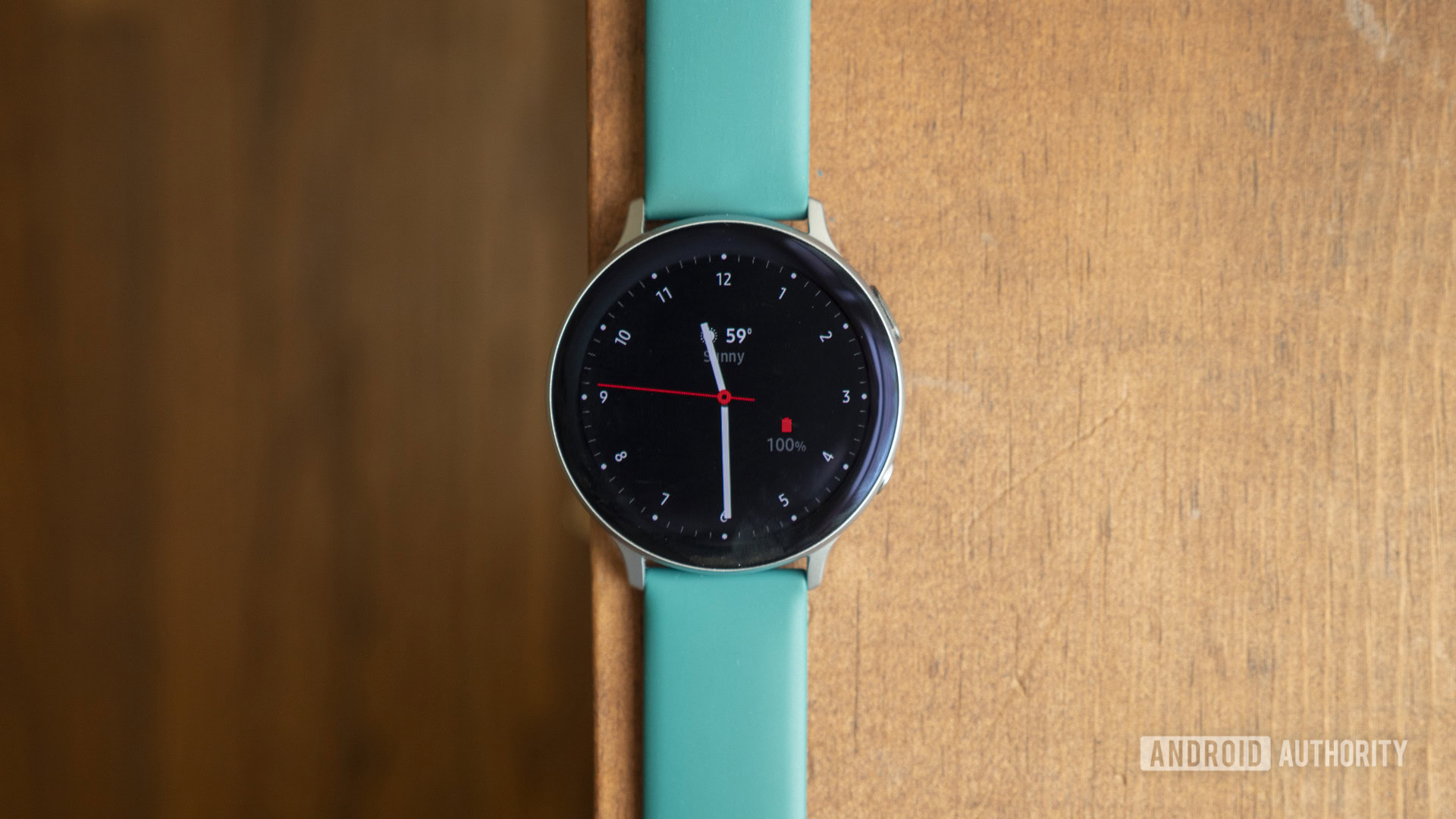 A Samsung Galaxy Watch Active 2 rests on a wooden surface displaying watch face.