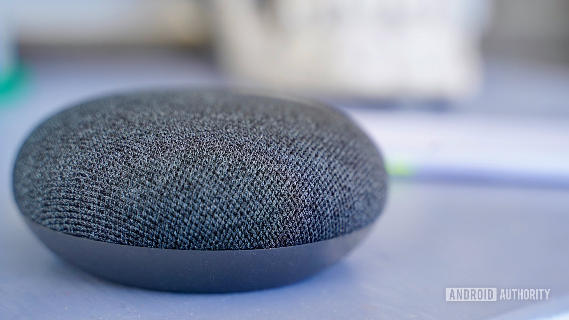 A Google Nest Mini in charcoal on a purple table