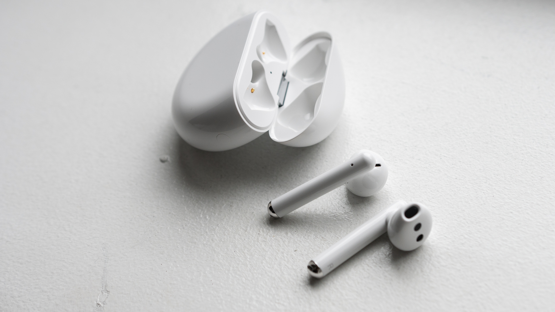 Huawei Freebuds 3 earbuds next to open charging case on white background.