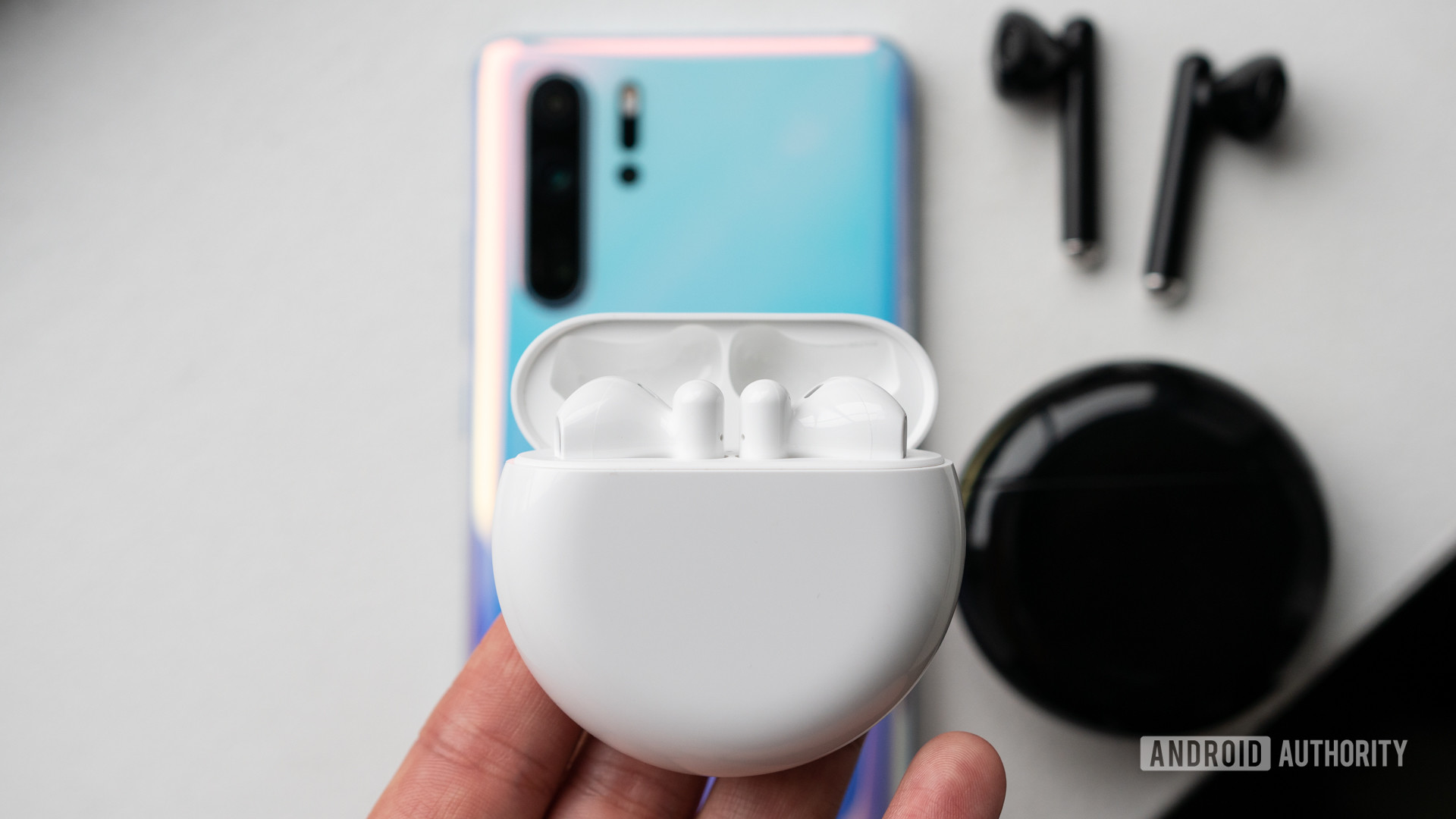 White Huawei Freebuds 3 in its charging case pictured alongside P30 Pro and the black color