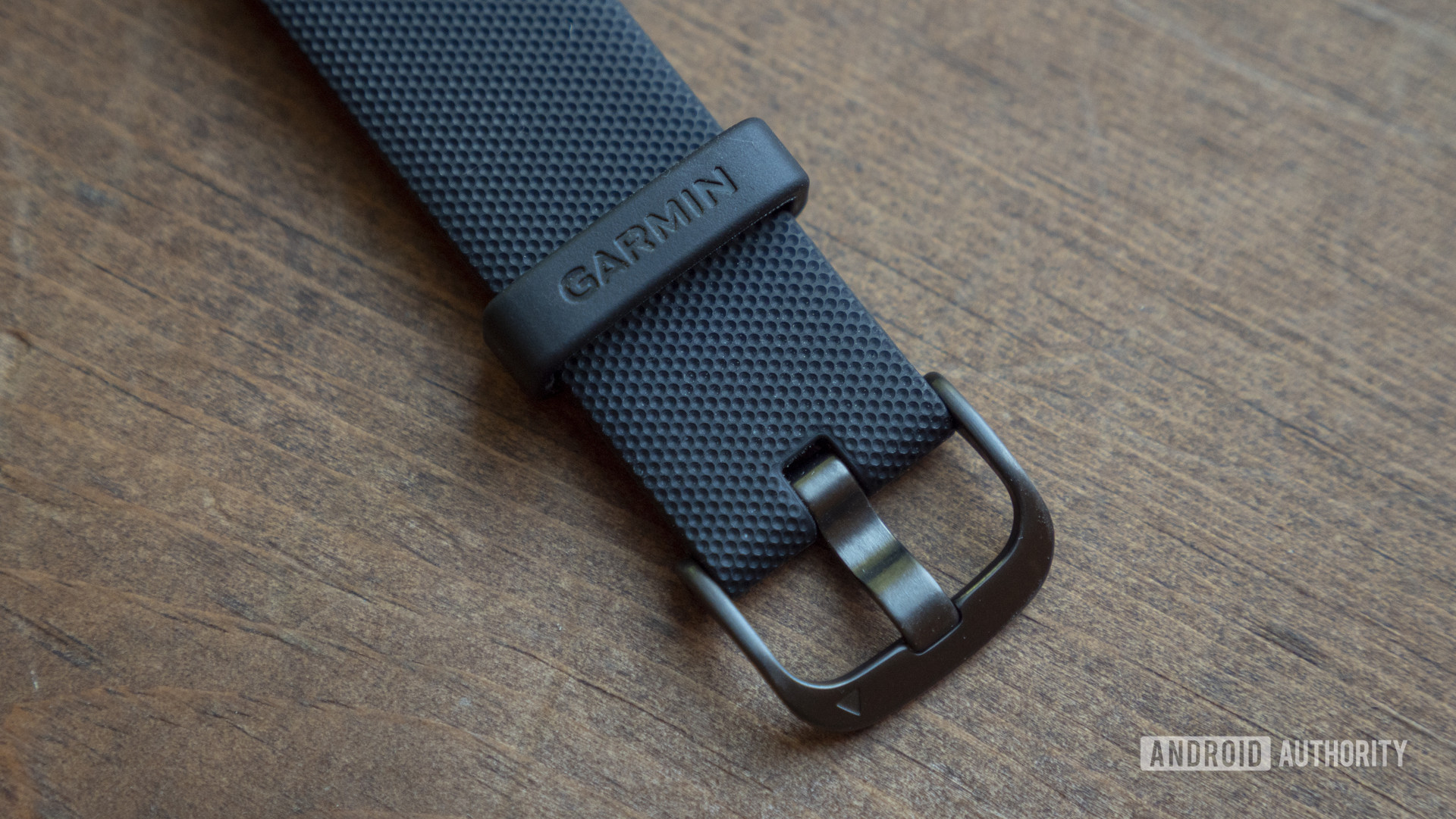 A close up image focuses on a user's black silicon watch strap. 
