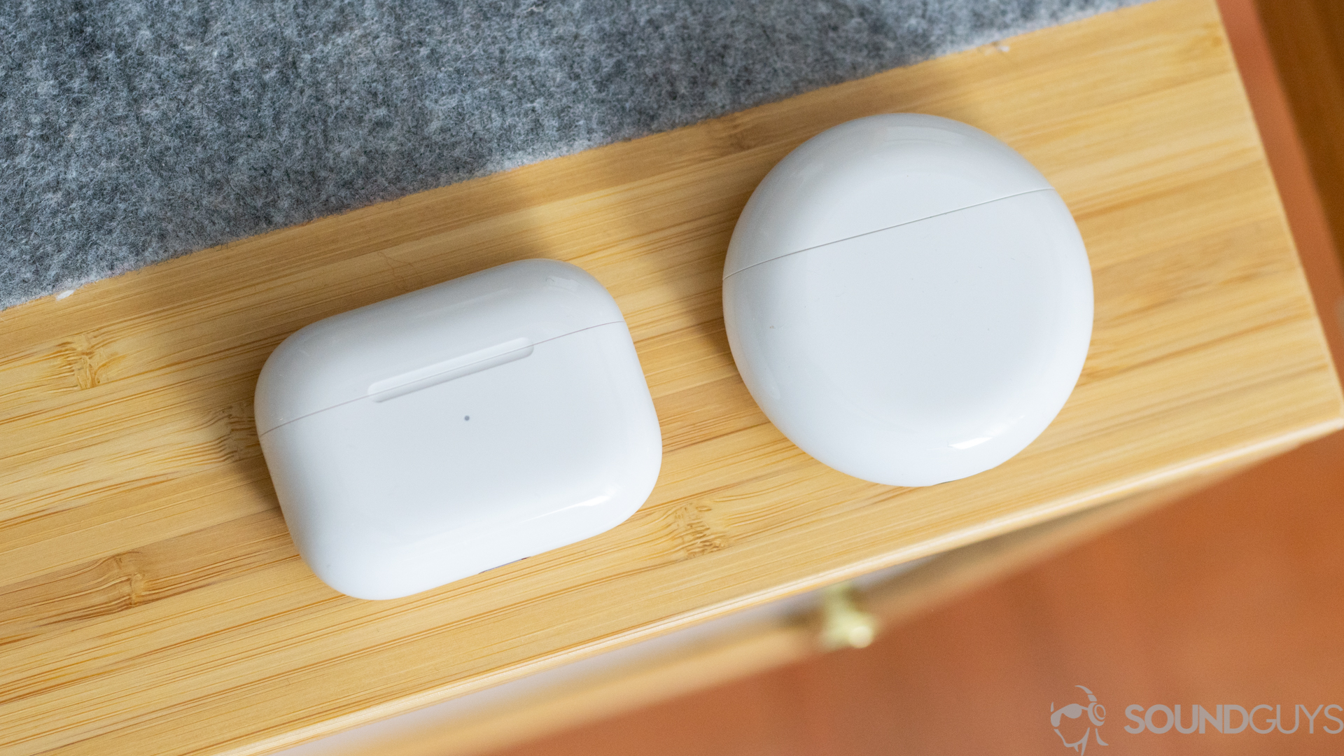 Both white charging cases pictured from above on a wood desk