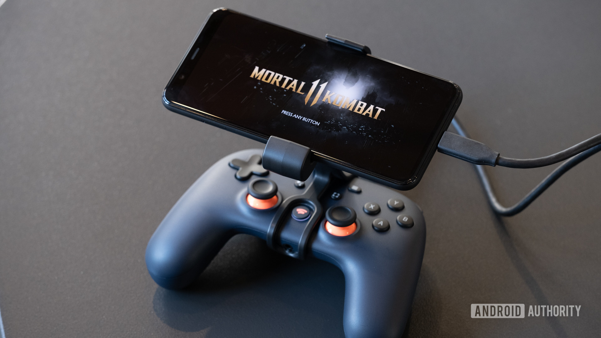 Google Stadia controller with phone mounted showing Mortal Kombat on the screen.