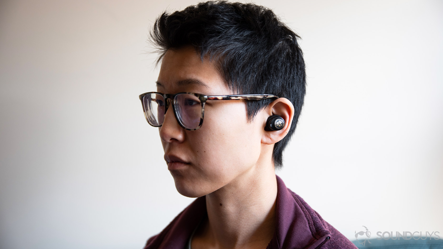 A picture of the JLab JBuds Air Icon true wireless earbuds worn by a woman looking to the left of the frame.