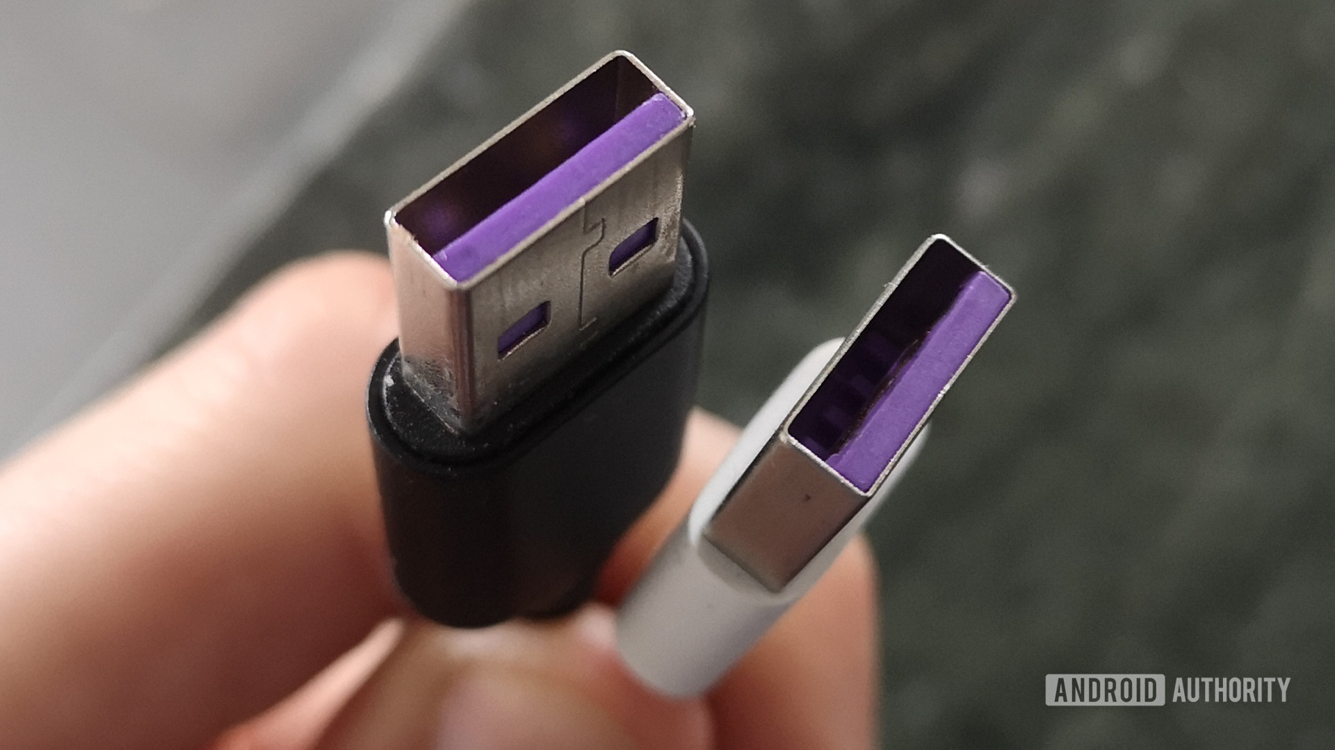 The ends of a USB cable being held by a hand.