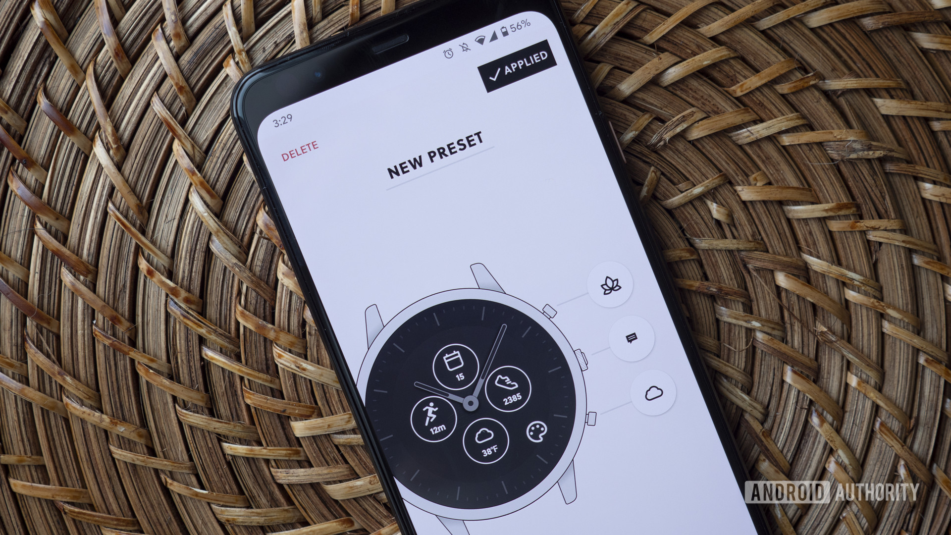A smartphone paired to a Fossil hybrid smartwatch displays the customization options available in the company's companion app.