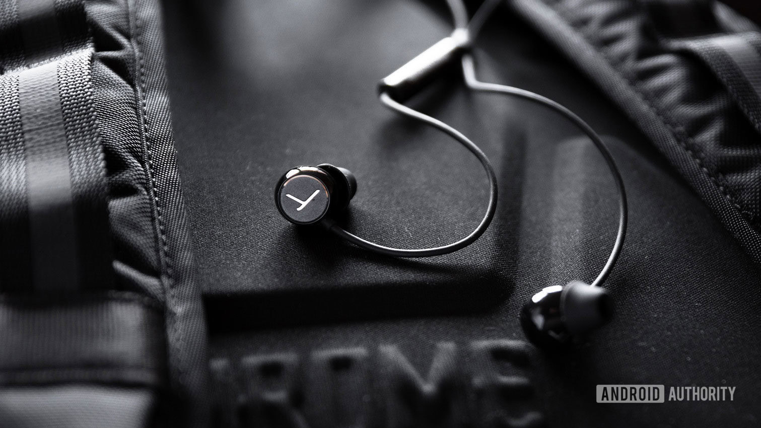 The beyerdynamic Soul Byrd wired earphones in black against a black backpack.