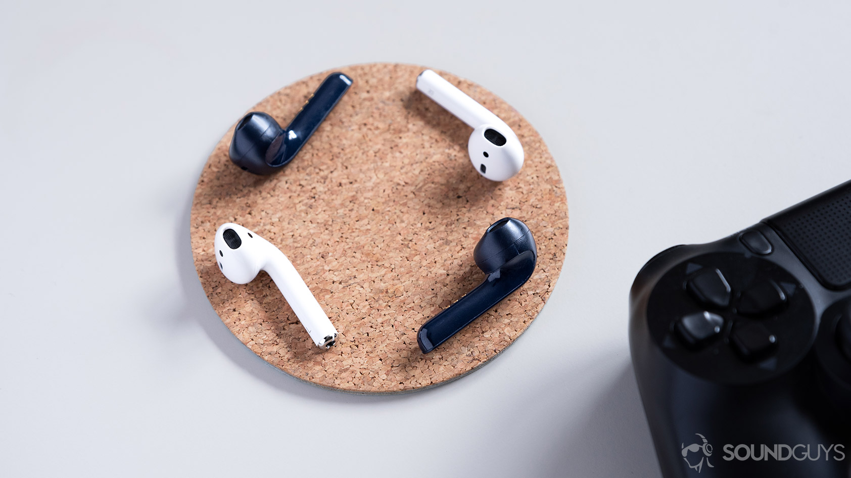 A picture of the Mobvoi TicPods 2 Pro true wireless earbuds compared to the Apple AirPods on a cork coaster.