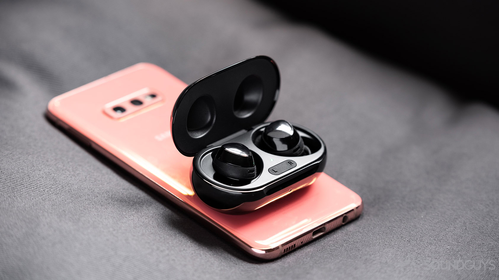 Samsung Galaxy S10e 위에 Wireless PowerShare를 사용하는 Samsung Galaxy Buds Plus 완전 무선 이어버드 사진.