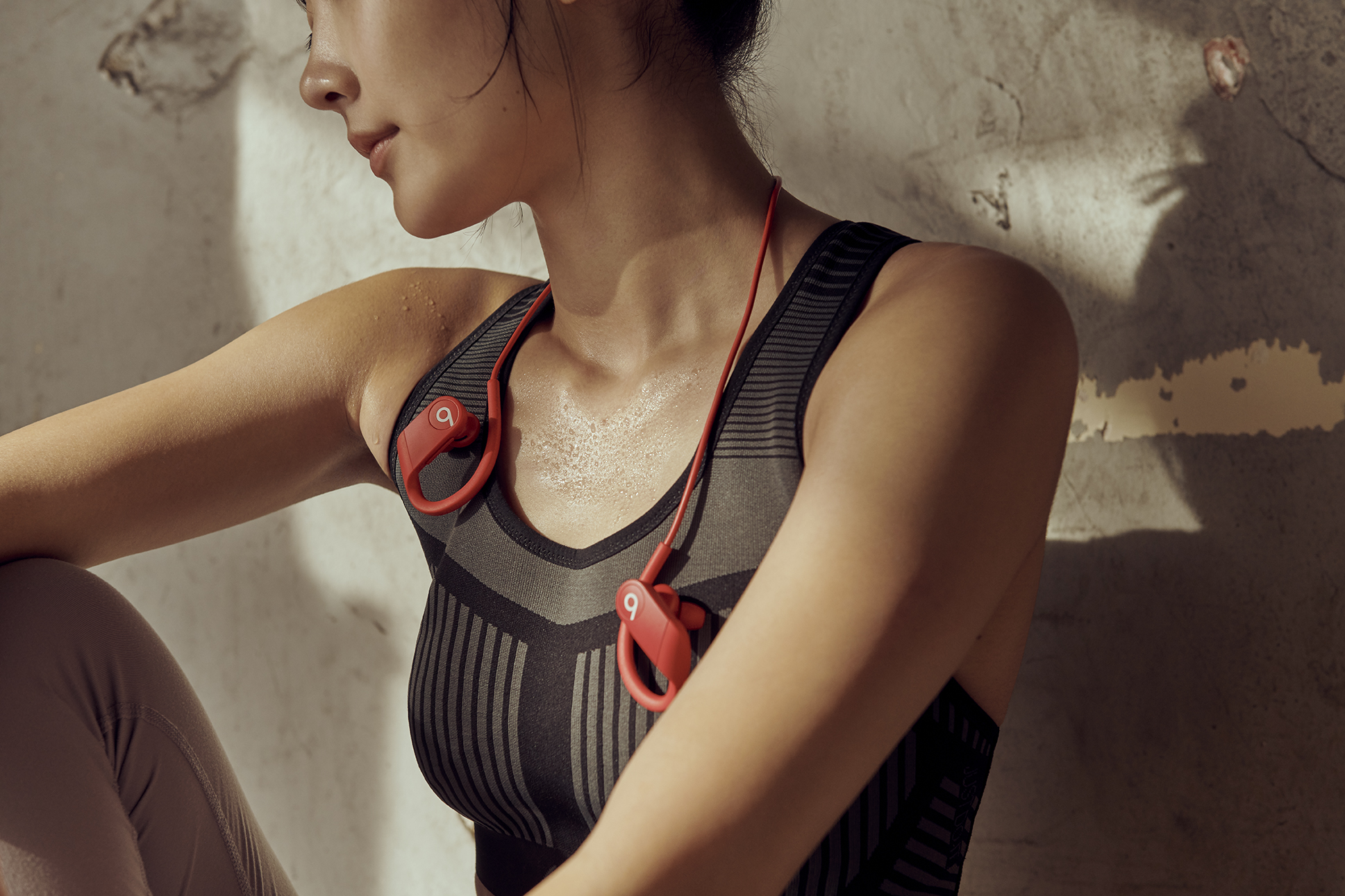 Lifestyle image of a woman wearing the Apple Powerbeats in red.