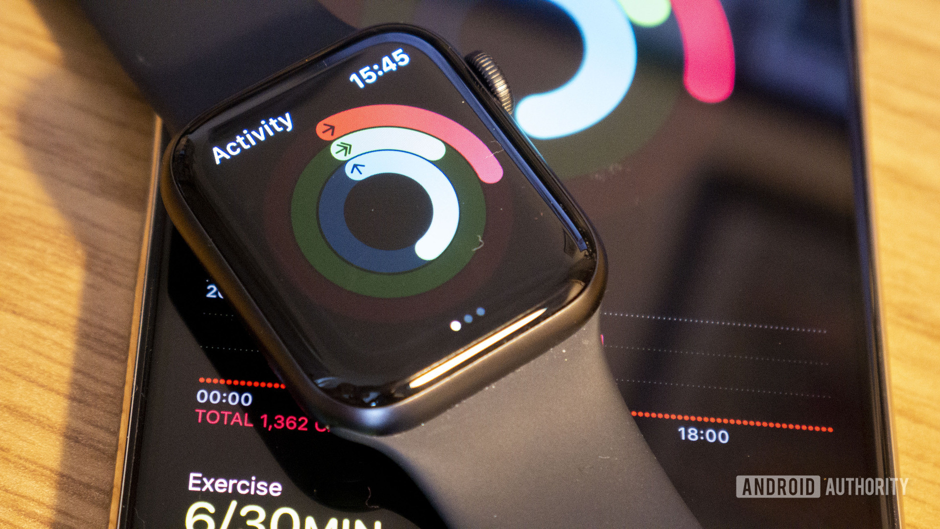 An Apple Watch Watch 5 rests on an iPhone, displaying a users activity and calorie tracking stats.
