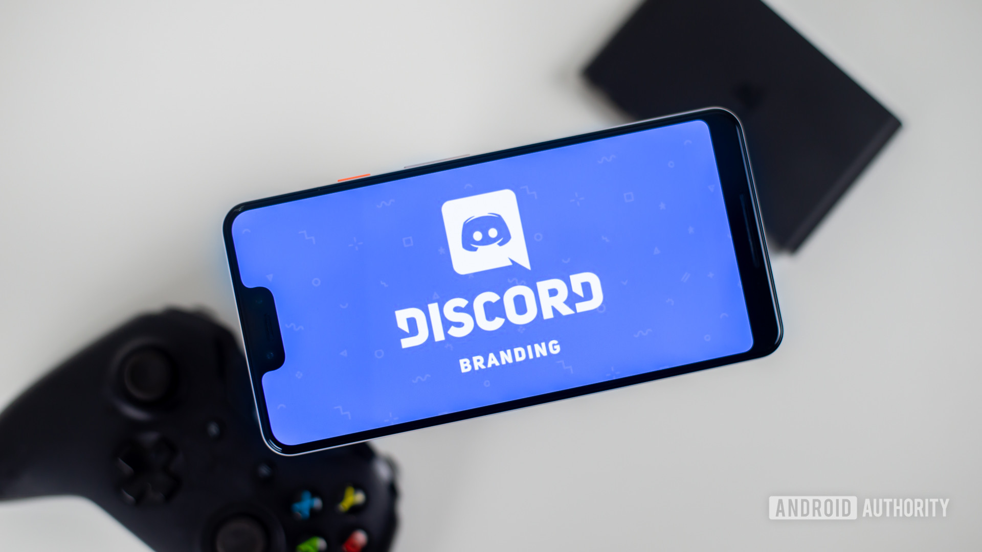 Discord on smartphone next to gamepad stock photo 1