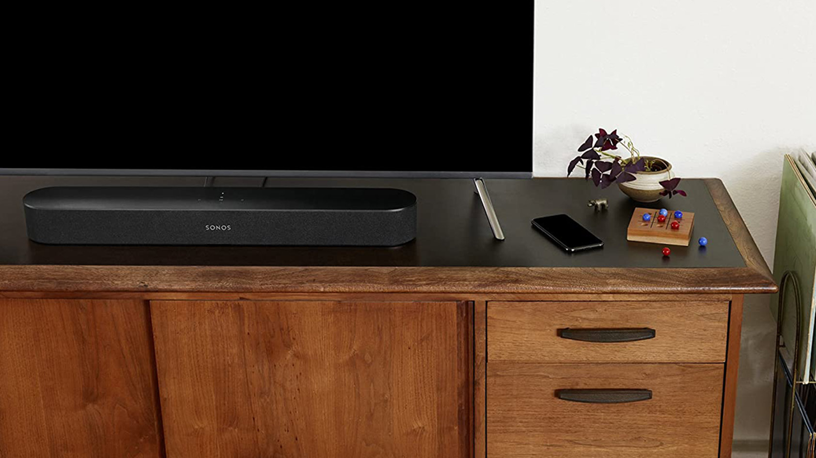 Een afbeelding van de Sonos Beam soundbar in het zwart op een tv-meubel.