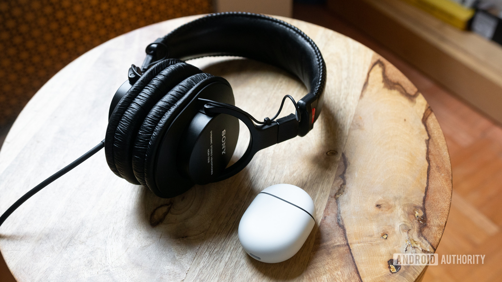 Sony MDR-7506 headphones and new Google Pixel Buds on a wooden stool