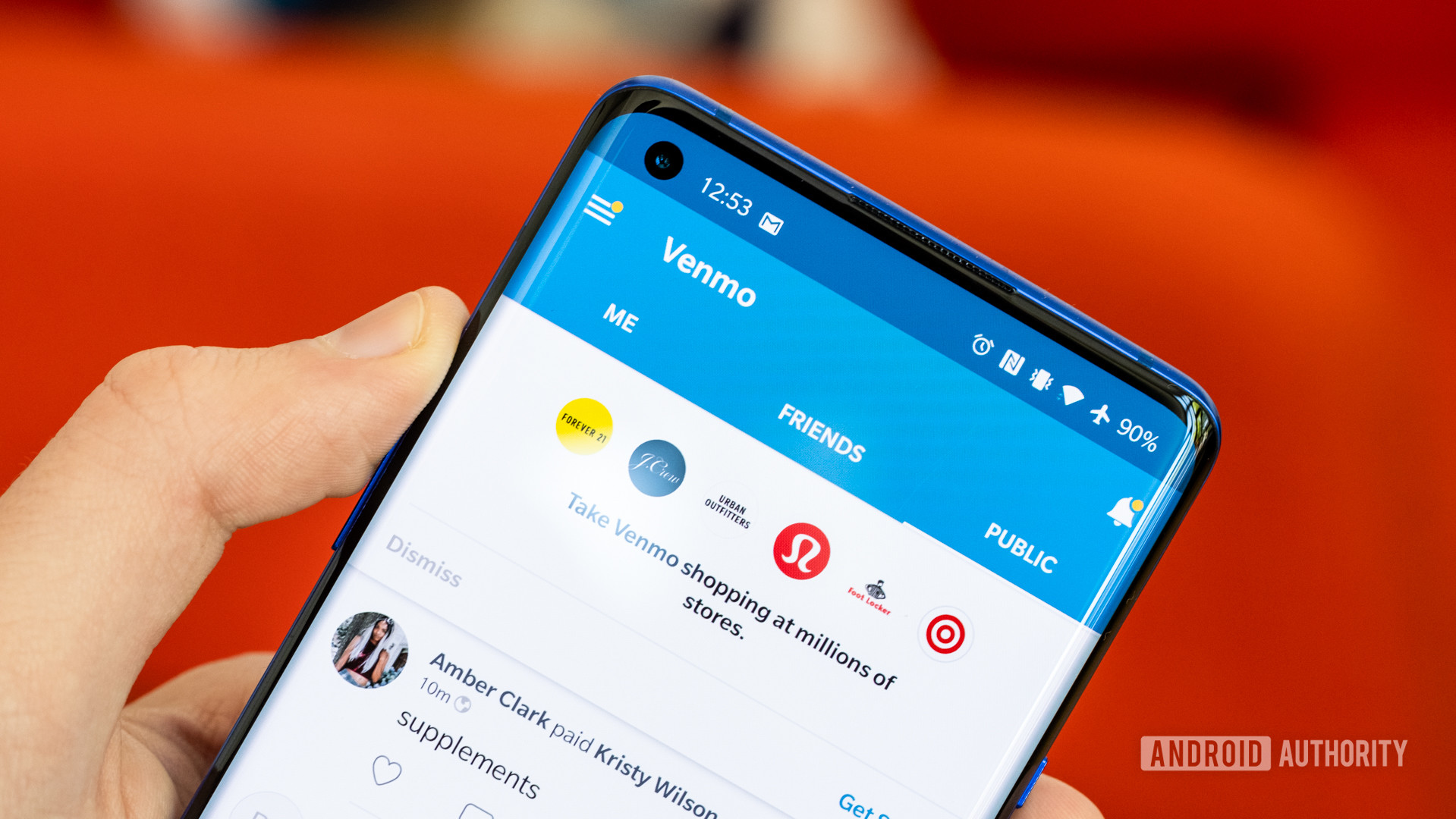 The Venmo app running on a smartphone being held in a hand against a blurry red background.