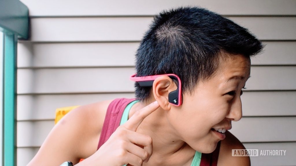 Photo of the Aftershokz titanium bone conduction headphones worn by a woman in profile.