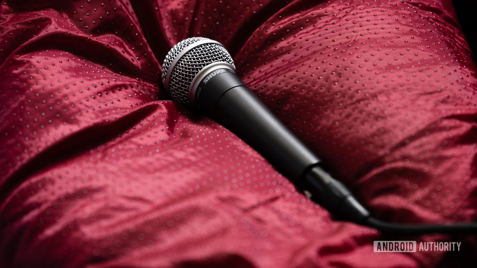 A picture of the Shure SM58 dynamic microphone on red surface.