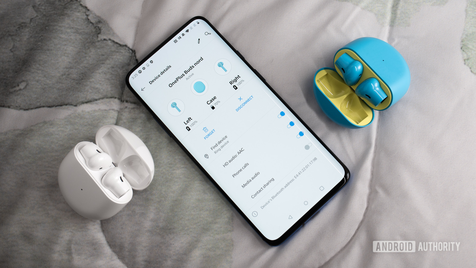 A picture of the OnePlus Buds true wireless earbuds in white and Nord Blue next to a OnePlus 7 Pro smartphone with the earbuds menu pulled up on the screen.
