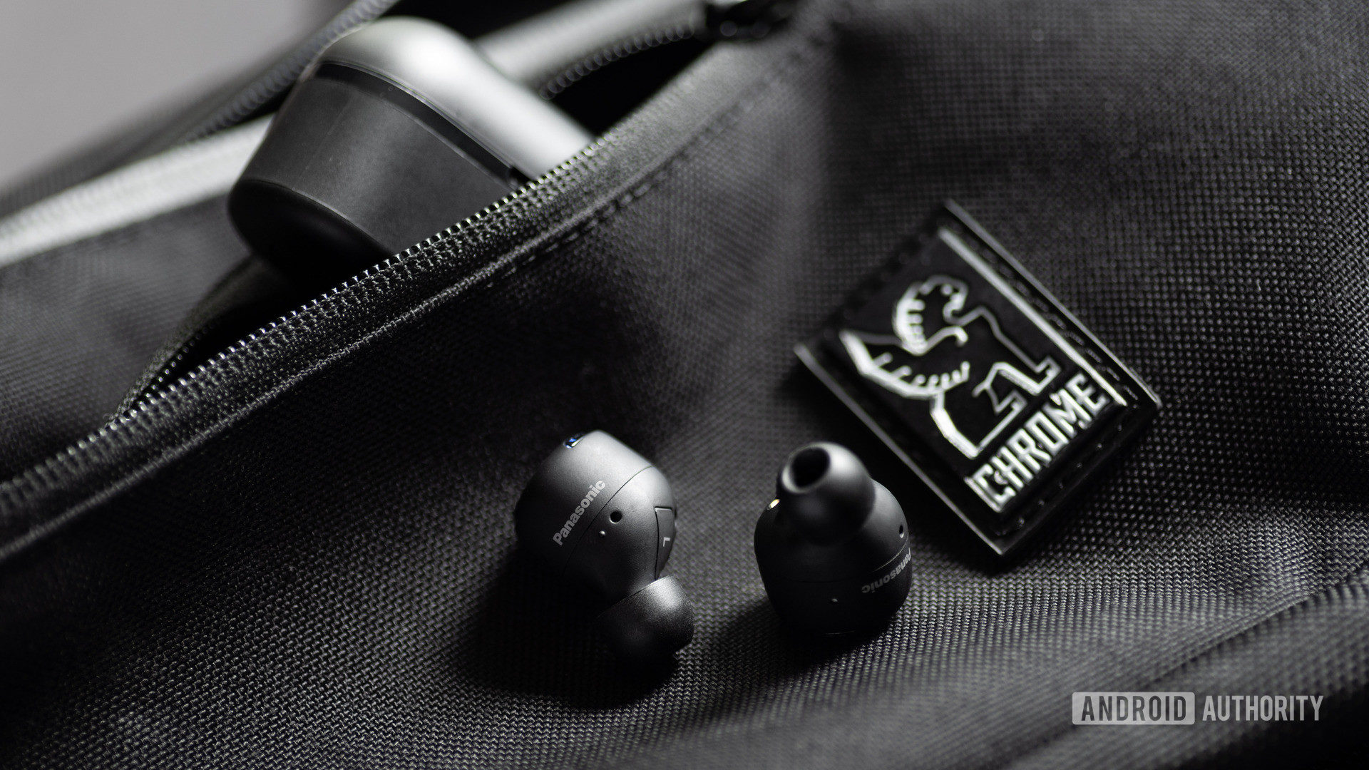 A picture of the Panasonic RZ-S500W noise cancelling earbuds on a Chrome sling bag with the case angled in the zippered pocket of the bag.