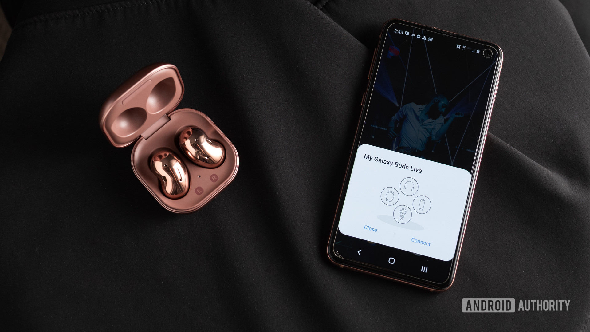 A picture of the Samsung Galaxy Buds Live noise cancelling true wireless earbuds in the open case next to a Samsung Galaxy S10e smartphone with quick pairing.