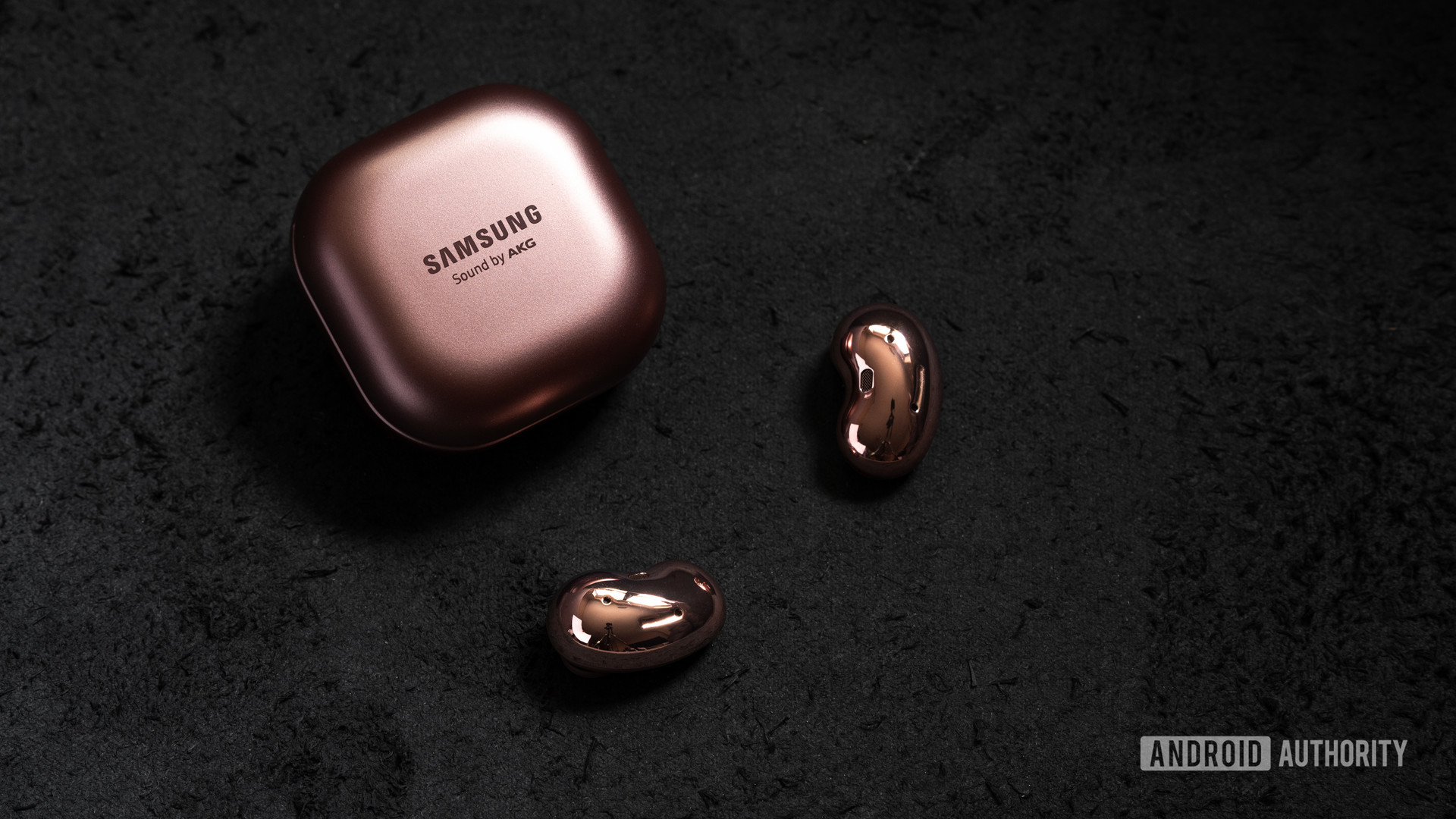 A picture of the Samsung Galaxy Buds Live noise cancelling true wireless earbuds outside of the closed case and on a black surface.