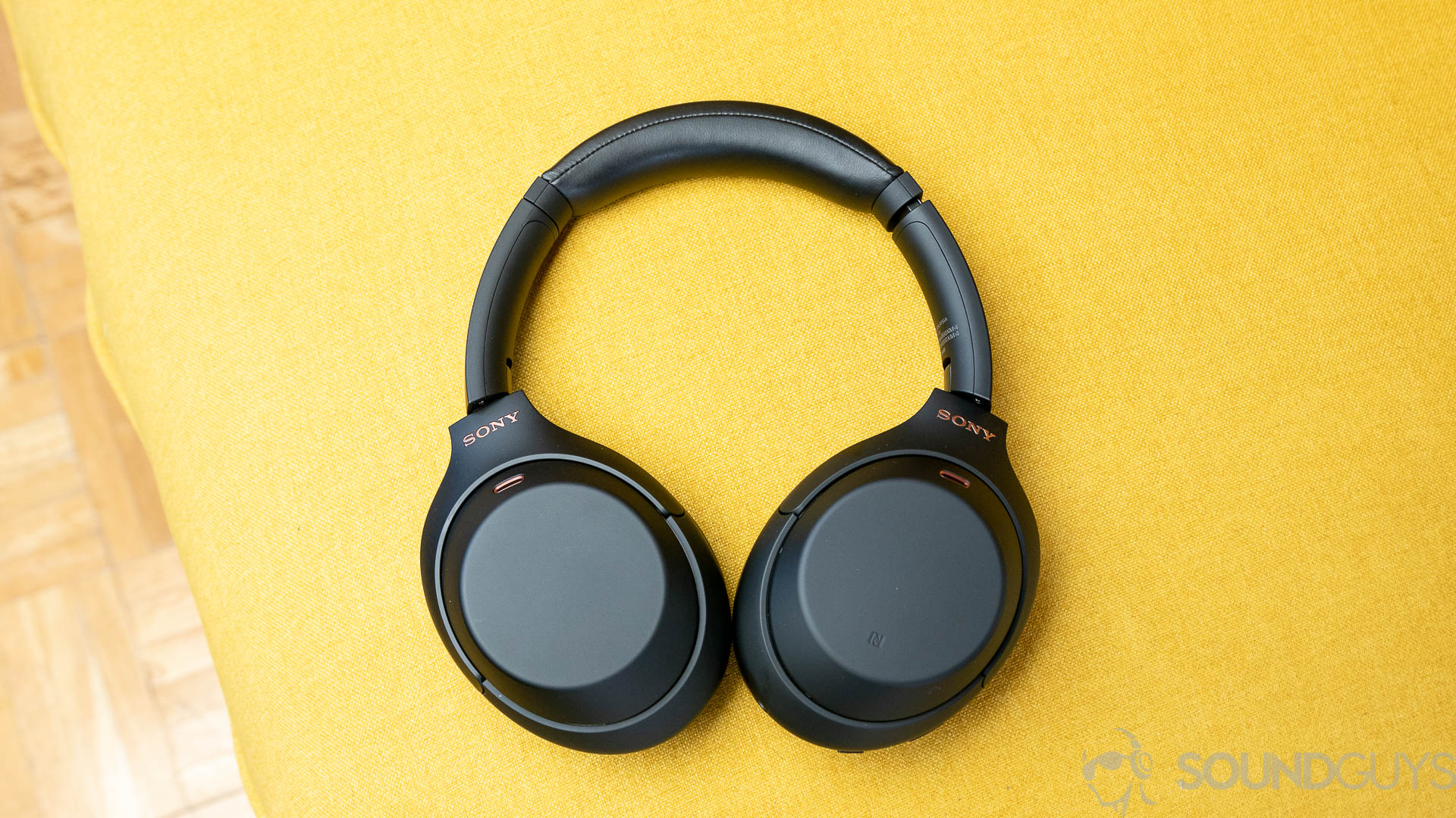 An aerial photo of the Sony WH 1000XM4 noise cancelling headphones full yellow backdrop.