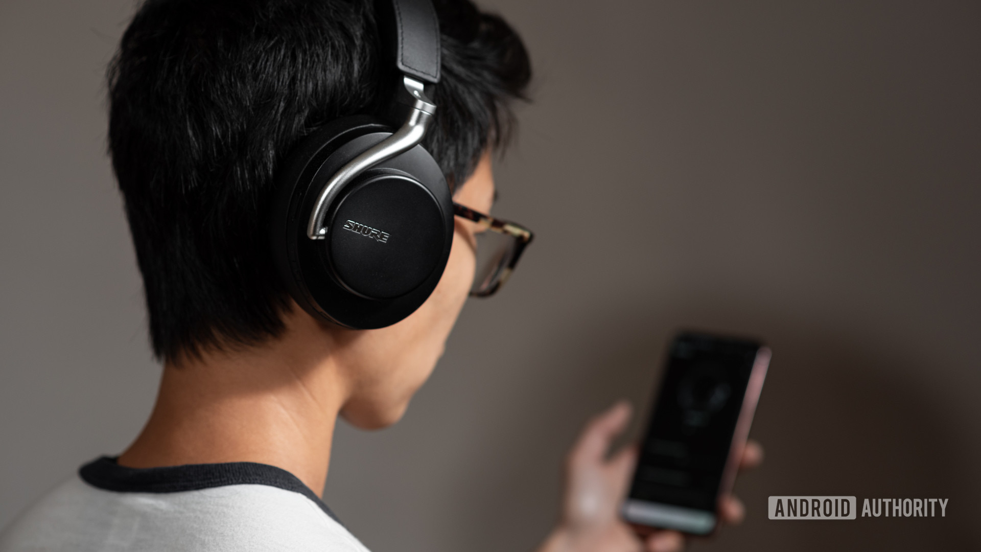 The Shure Aonic 50 noise cancelling headphones worn by a woman using the Shure mobile app.