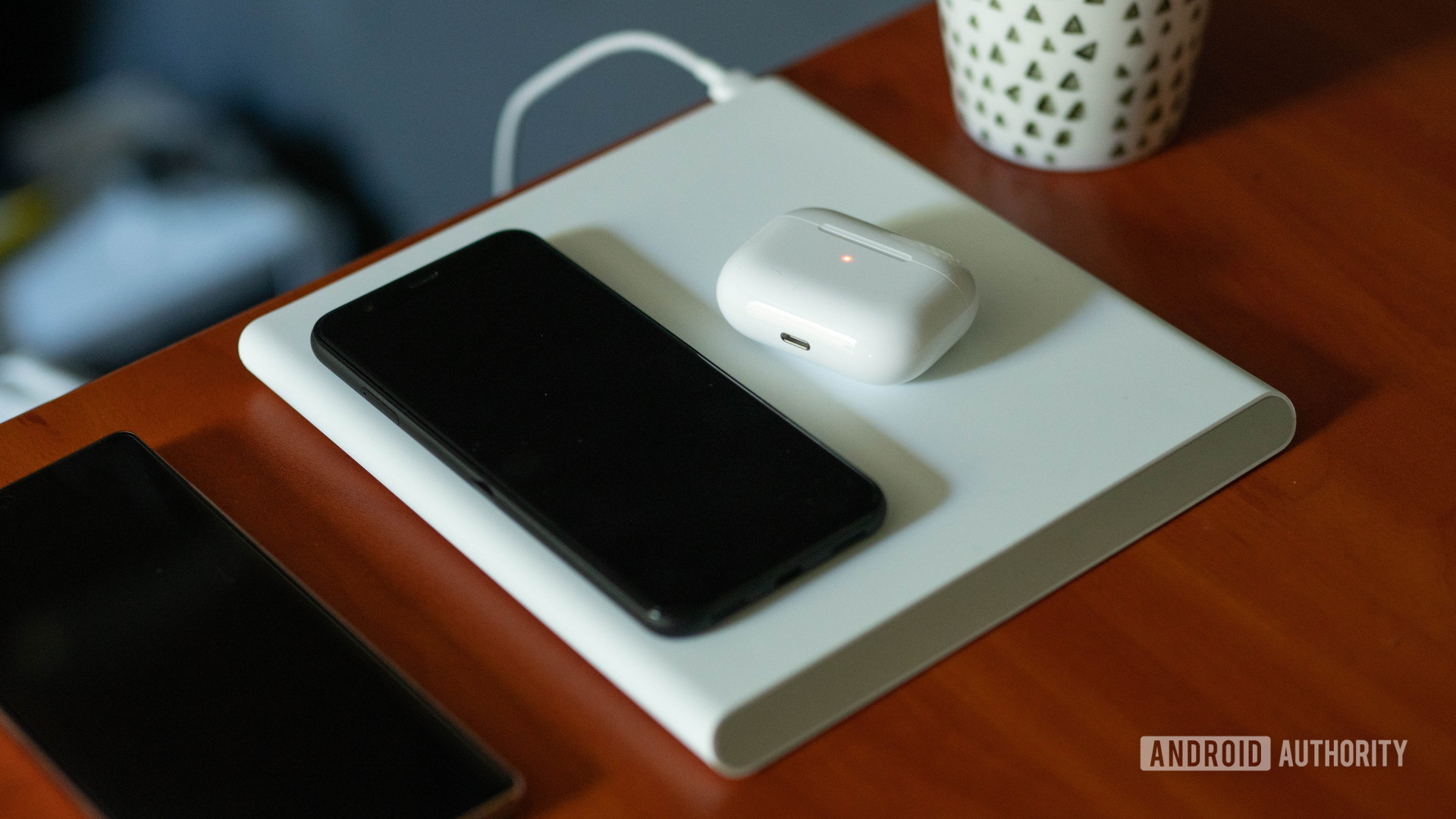 Xiaomi Mi 20W Smart Tracking Wireless Charging Pad charging a phone and some Airpods